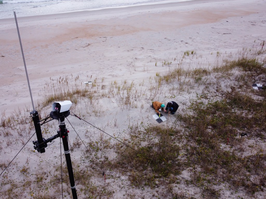 Aerial view looking down from beach camera on researchers collecting GPS data